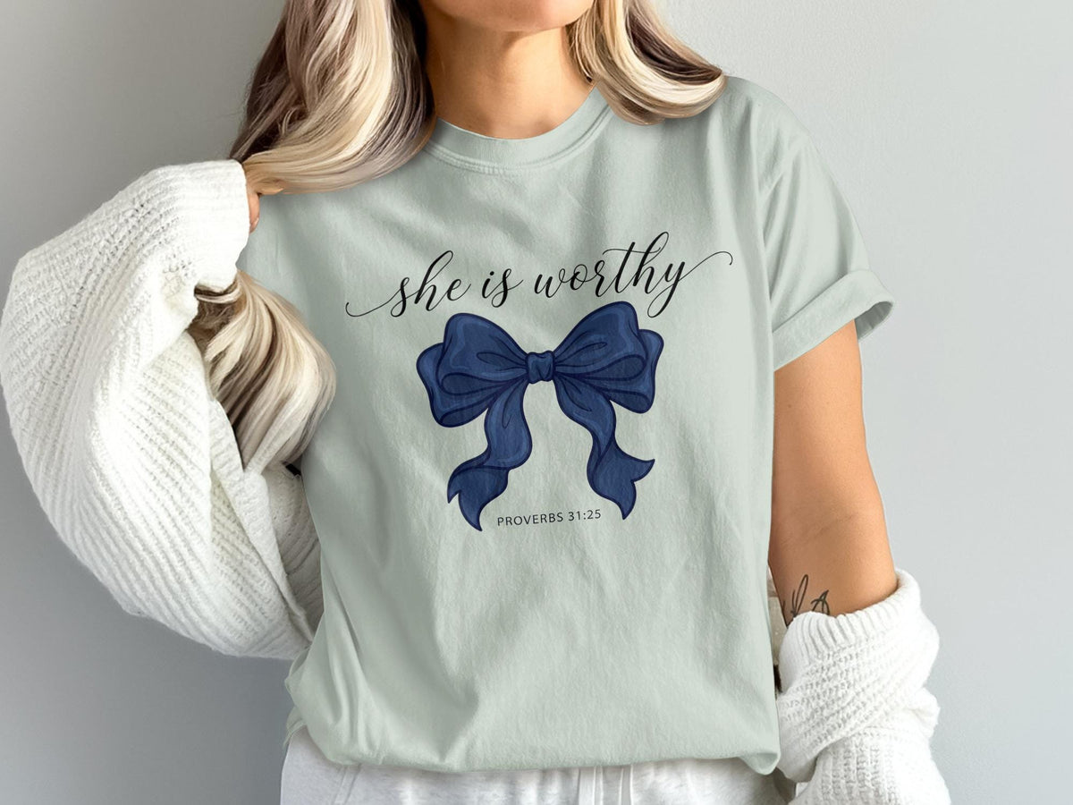 Light blue t-shirt with "she is worthy" and a navy blue bow.