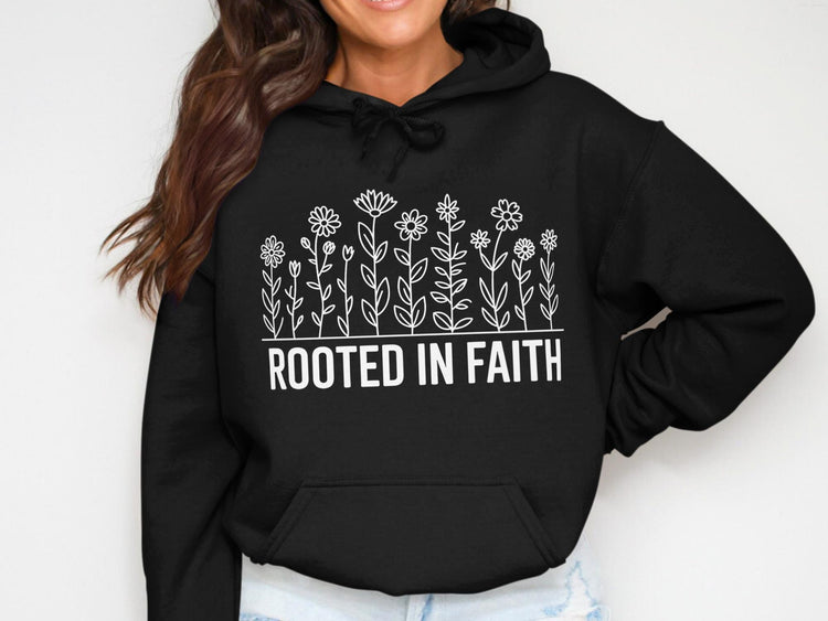 Black hoodie with white floral design and text "ROOTED IN FAITH"
