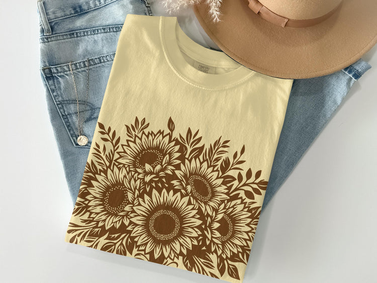 Yellow t-shirt with brown sunflower graphic on denim with a tan hat.