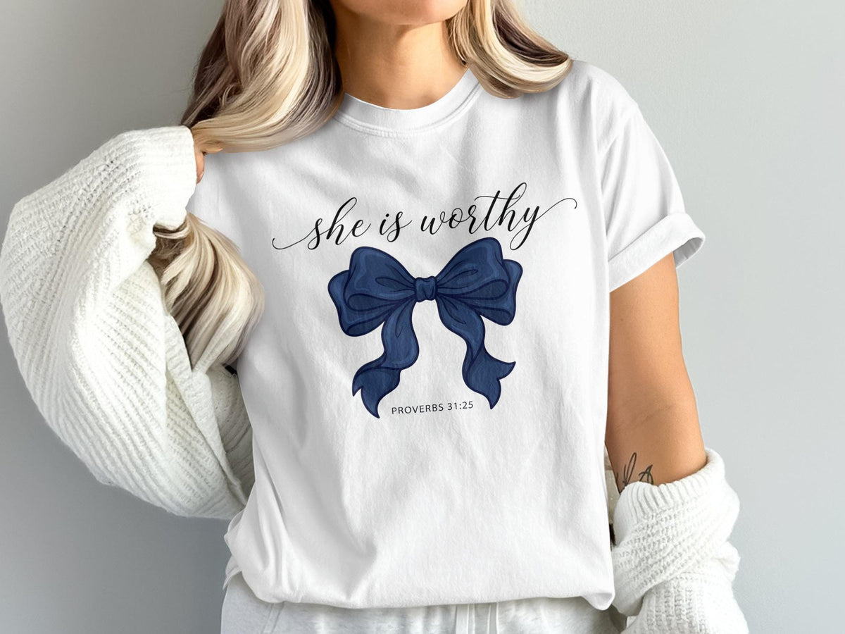 White t-shirt with blue bow graphic and text "she is worthy PROVERBS 31:25".