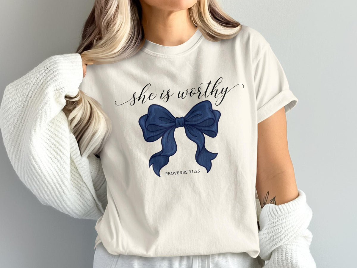 Cream t-shirt with navy blue bow graphic and text "she is worthy" and "PROVERBS 31:25".