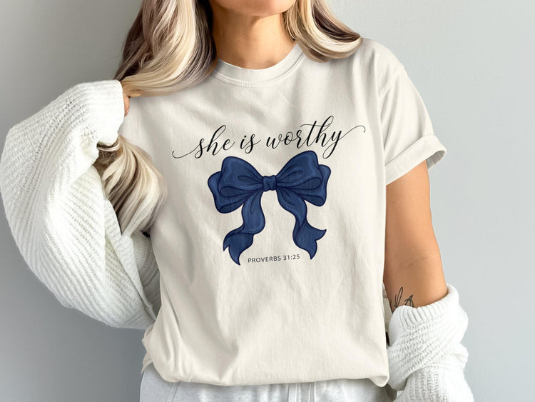 Cream t-shirt with navy blue bow graphic and text "she is worthy" and "PROVERBS 31:25".