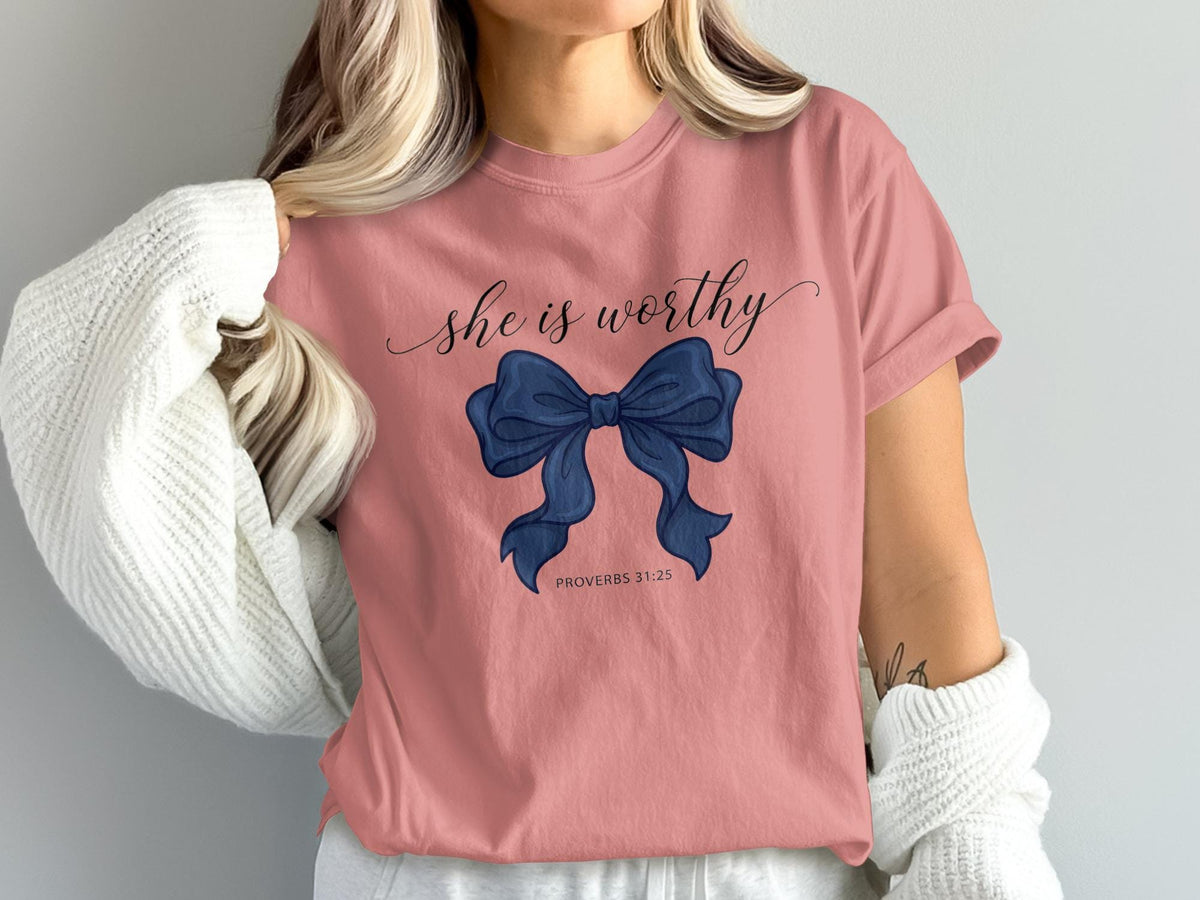 Pink t-shirt with "she is worthy" and a navy blue bow, Proverbs 31:25.