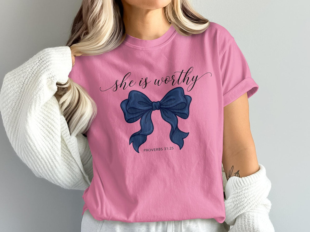 Pink t-shirt with "she is worthy" text and navy bow graphic.
