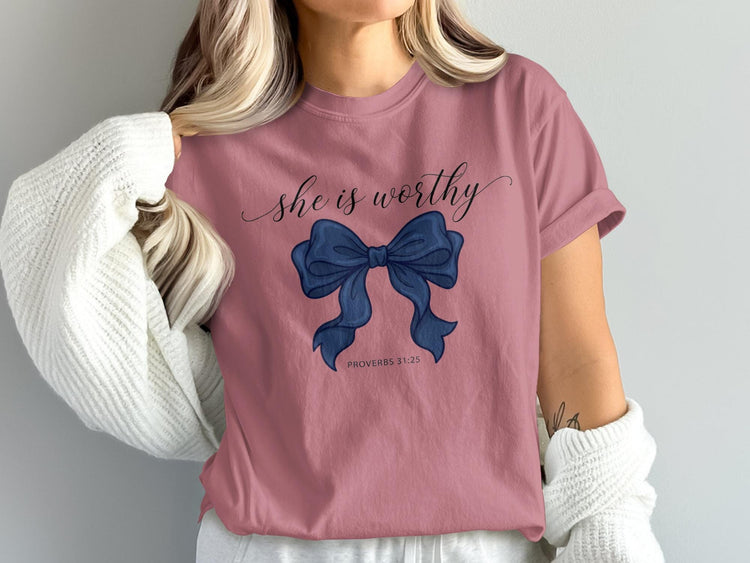 Pink t-shirt with "she is worthy" text and a blue bow graphic.
