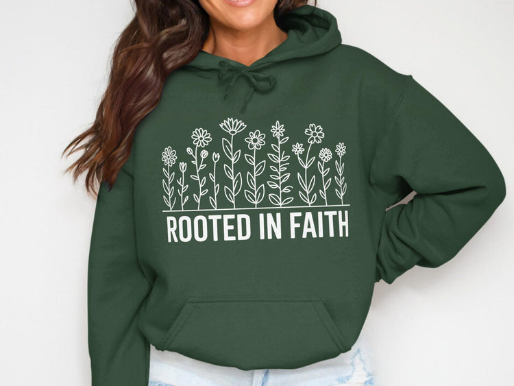 Dark green hoodie with white line drawing of flowers and text "ROOTED IN FAITH".