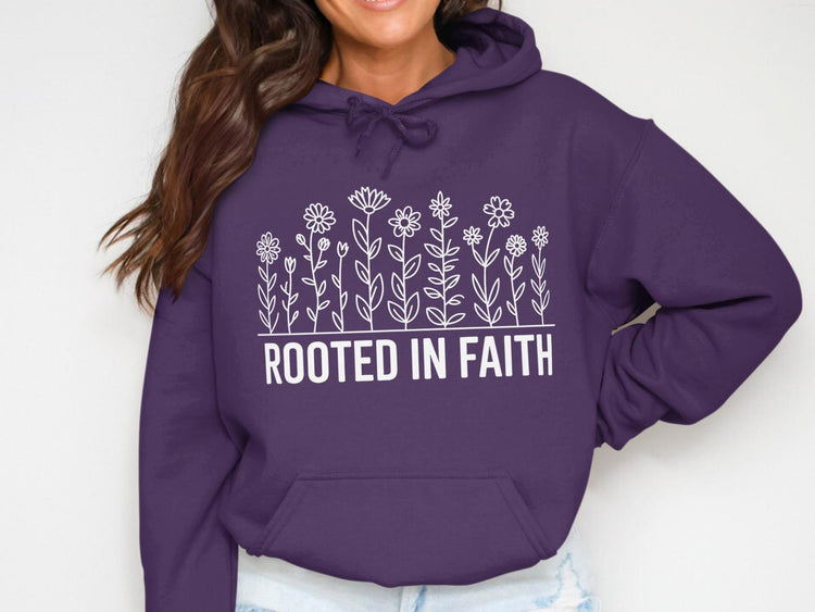 Purple hoodie with white floral design and text "ROOTED IN FAITH".