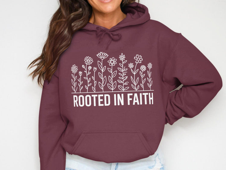 Maroon hoodie with white floral graphic and "ROOTED IN FAITH" text.