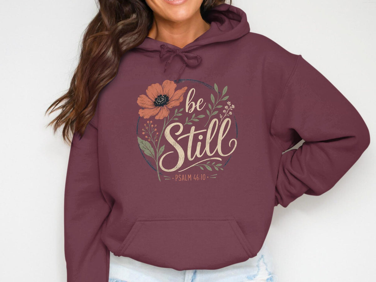 Burgundy hoodie with "be Still" and Psalm 46:10 floral graphic.
