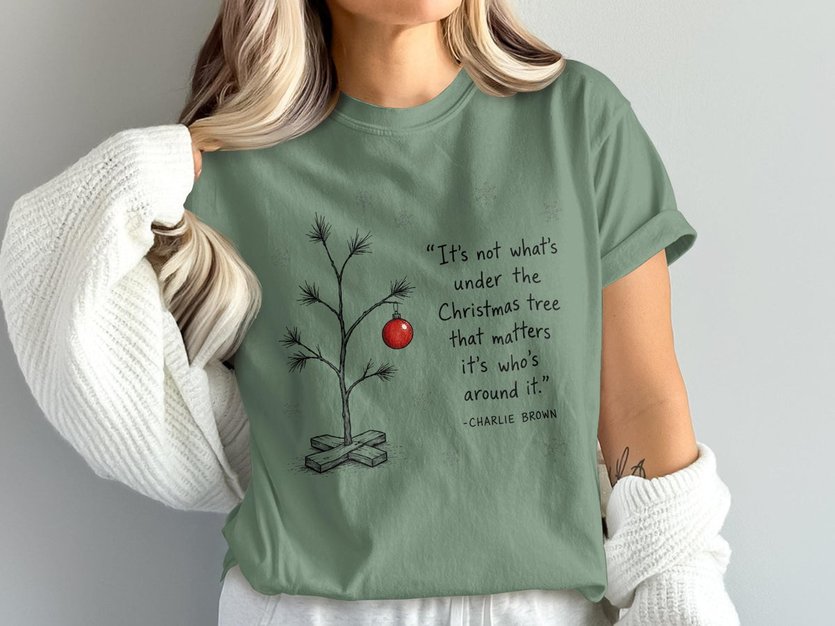 Green t-shirt with Charlie Brown quote and a single ornament on a bare Christmas tree.