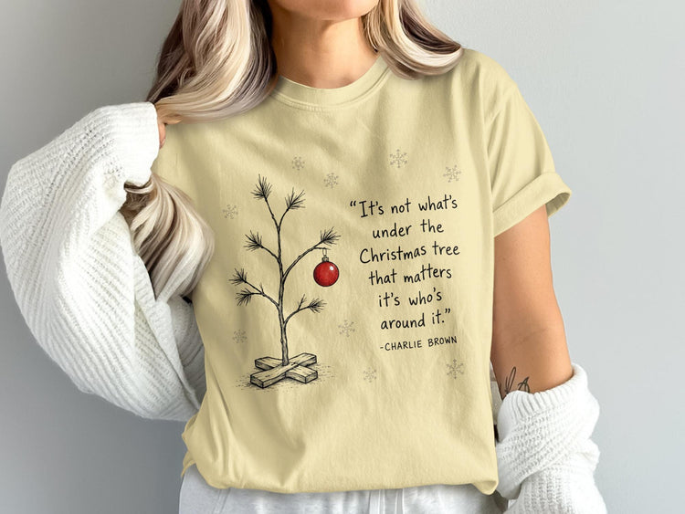 Light yellow t-shirt with a sparse Christmas tree drawing and Charlie Brown quote.