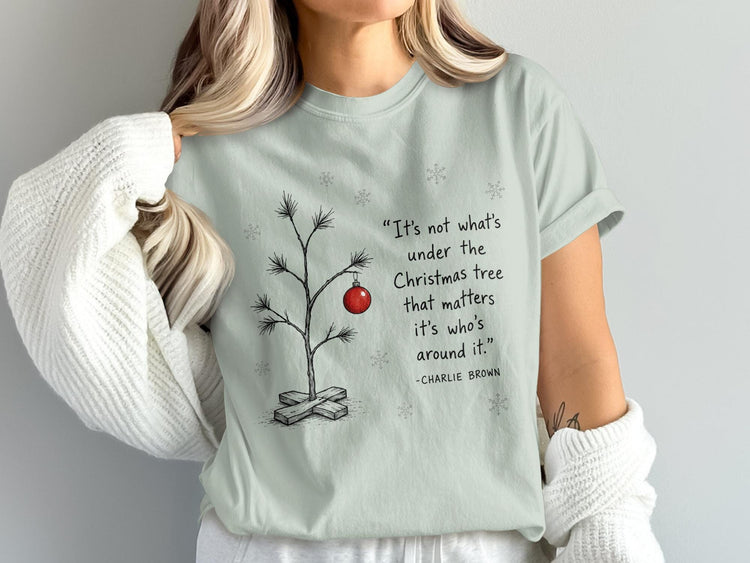 Charlie Brown quote about Christmas trees on a light green t-shirt.