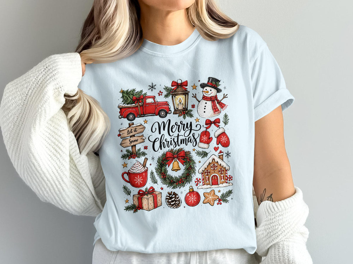 Light blue t-shirt with a "Merry Christmas" graphic featuring a truck, snowman, wreath, and gingerbread house.