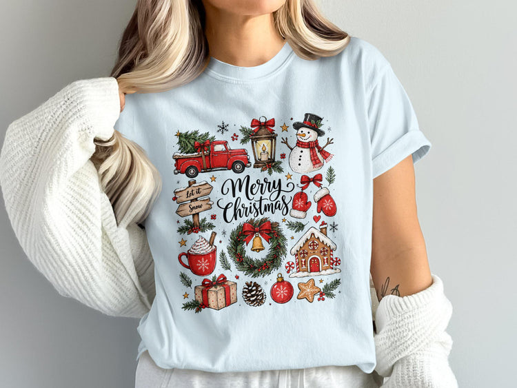 Light blue t-shirt with a "Merry Christmas" graphic featuring a truck, snowman, wreath, and gingerbread house.