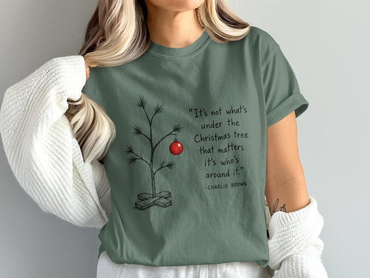 Green t-shirt with Charlie Brown quote about Christmas and a bare tree with one ornament.