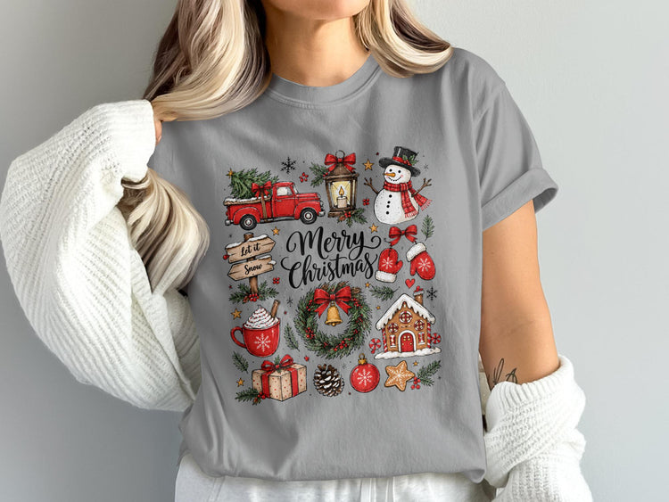 Merry Christmas graphic with truck, snowman, gingerbread house, and gifts on gray t-shirt.